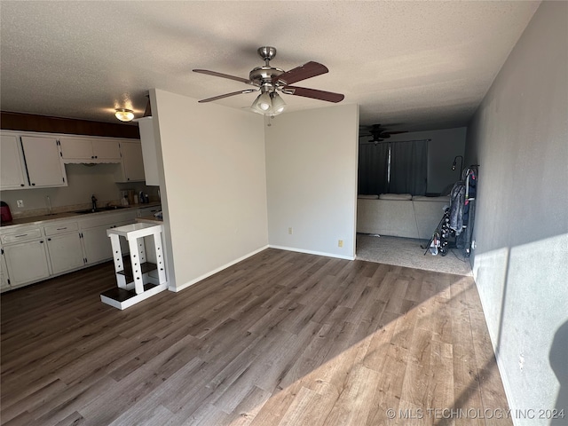 unfurnished living room featuring ceiling fan, hardwood / wood-style flooring, a textured ceiling, and sink