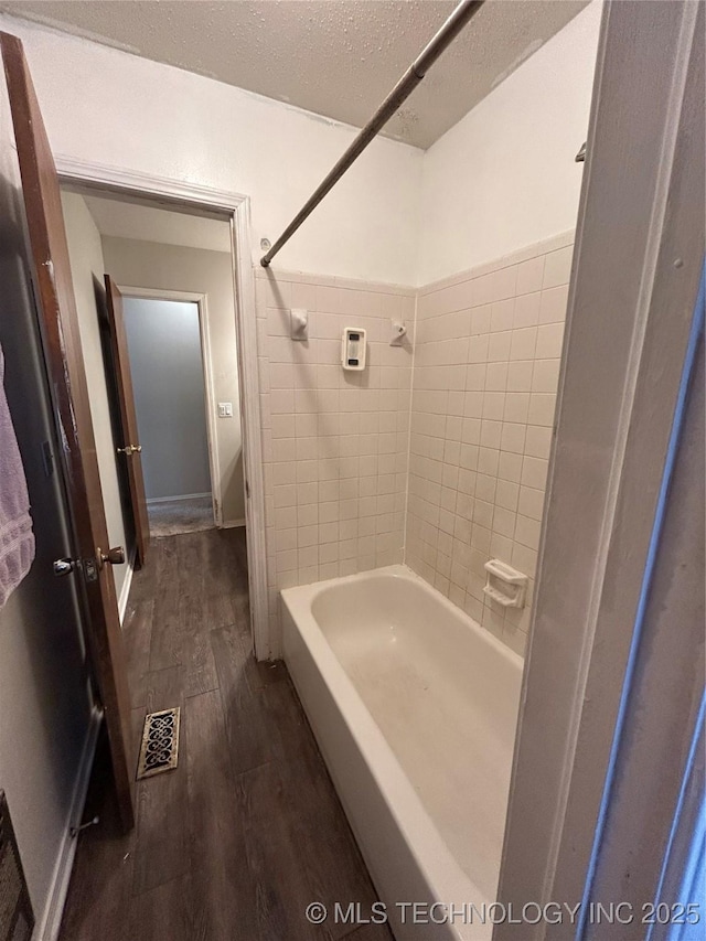 bathroom with tiled shower / bath, hardwood / wood-style floors, and a textured ceiling