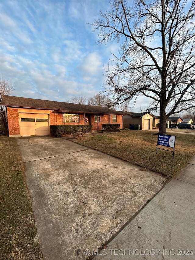 single story home featuring brick siding, a front yard, concrete driveway, and an attached garage