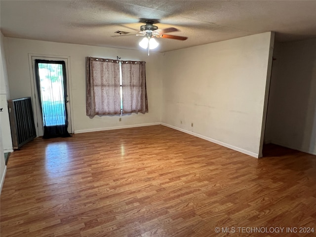 unfurnished room featuring ceiling fan, wood-type flooring, and a textured ceiling