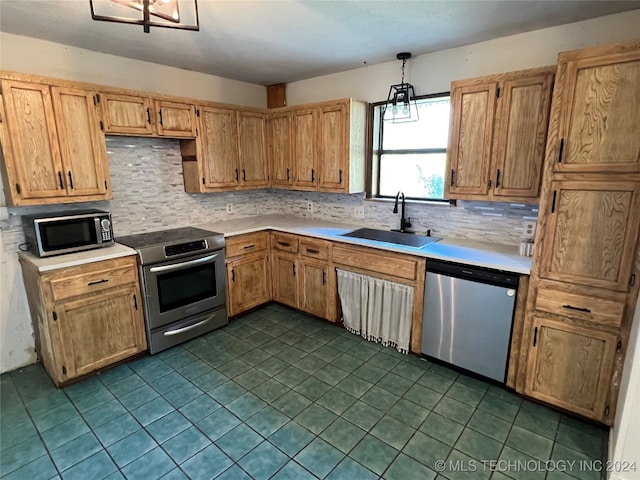 kitchen featuring pendant lighting, sink, stainless steel appliances, and backsplash