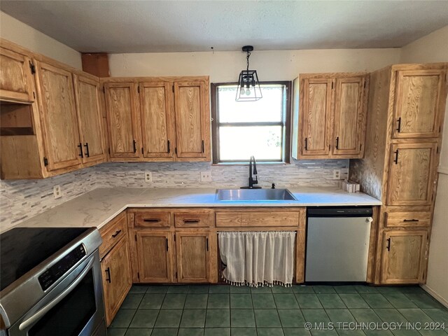 kitchen with hanging light fixtures, sink, dark tile patterned floors, backsplash, and appliances with stainless steel finishes