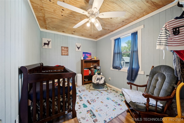 bedroom featuring ceiling fan, a nursery area, hardwood / wood-style flooring, and wood ceiling