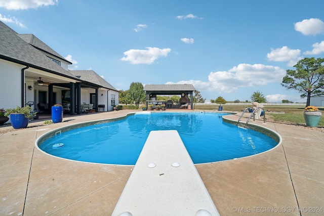 view of pool with a diving board, a patio, and ceiling fan