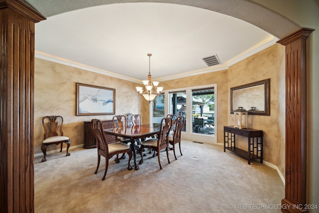 carpeted dining room with an inviting chandelier, decorative columns, and ornamental molding