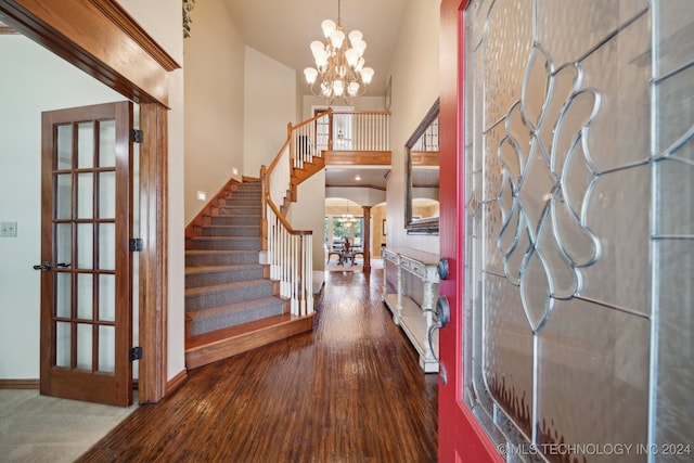 entrance foyer featuring wood-type flooring, an inviting chandelier, and high vaulted ceiling