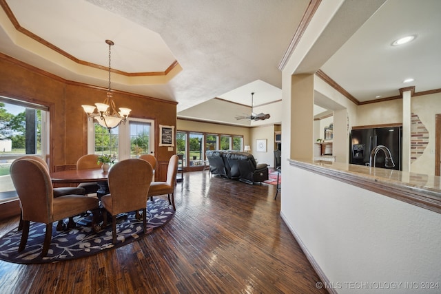 dining space with ceiling fan with notable chandelier, crown molding, a tray ceiling, and dark wood-type flooring