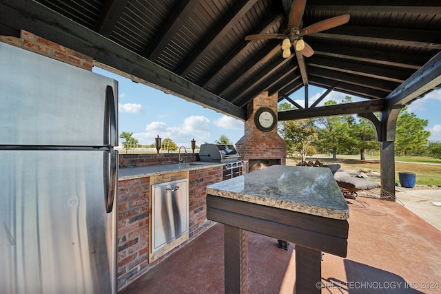 view of patio with a gazebo, ceiling fan, an outdoor brick fireplace, an outdoor kitchen, and sink