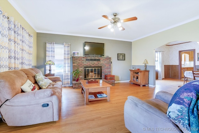 living room with crown molding, ceiling fan, a fireplace, and light hardwood / wood-style flooring