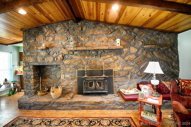 unfurnished living room featuring lofted ceiling with beams, a stone fireplace, wooden ceiling, and wood-type flooring