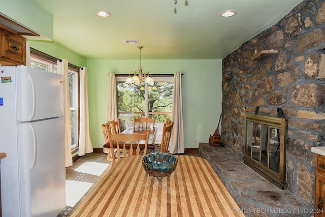 dining area with dark tile patterned flooring, a fireplace, and a chandelier