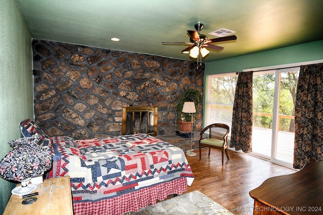 bedroom featuring a fireplace, wood-type flooring, access to outside, and ceiling fan