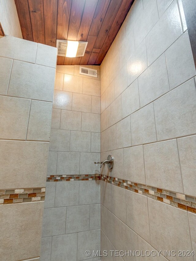 bathroom featuring tiled shower, visible vents, and wooden ceiling