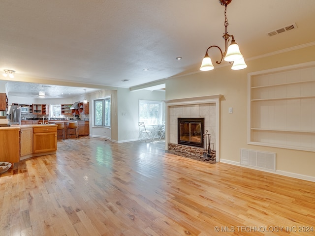 unfurnished living room featuring light hardwood / wood-style floors, ornamental molding, and a textured ceiling