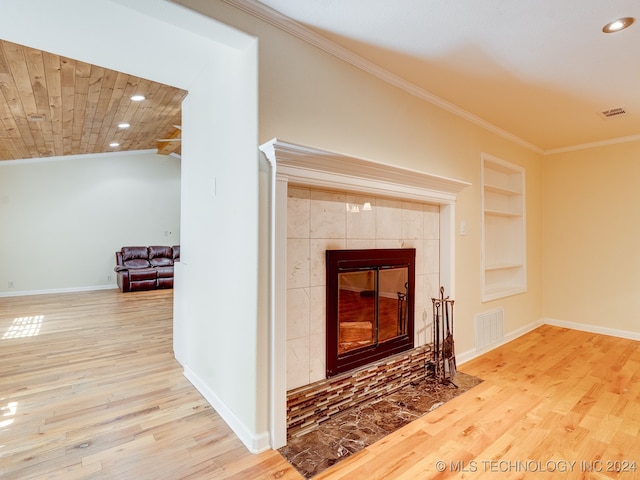 interior details with built in shelves, ornamental molding, a fireplace, and hardwood / wood-style floors