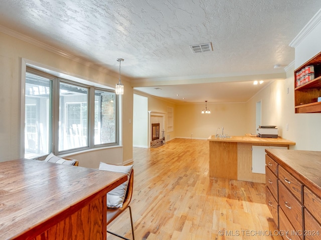kitchen with visible vents, hanging light fixtures, open shelves, crown molding, and light wood-style flooring