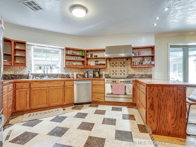 kitchen featuring range hood, open shelves, a sink, a peninsula, and stainless steel appliances