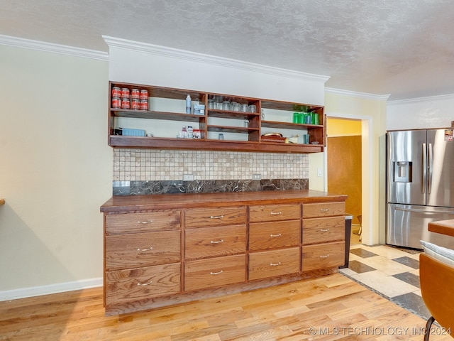 kitchen featuring stainless steel fridge, crown molding, open shelves, dark countertops, and light wood finished floors