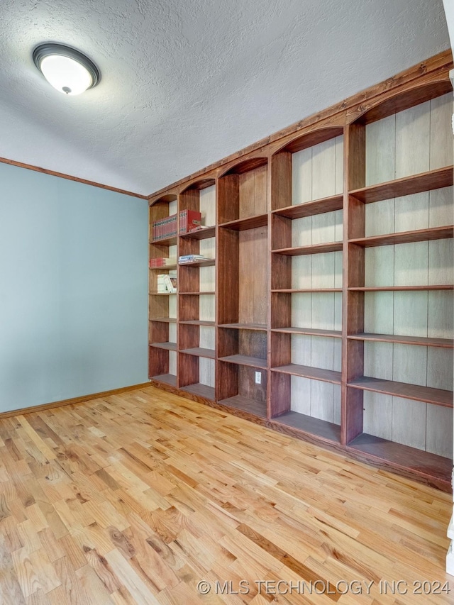 empty room with a textured ceiling, baseboards, and wood finished floors