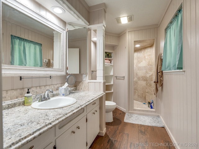 bathroom with a shower, toilet, hardwood / wood-style floors, decorative backsplash, and vanity