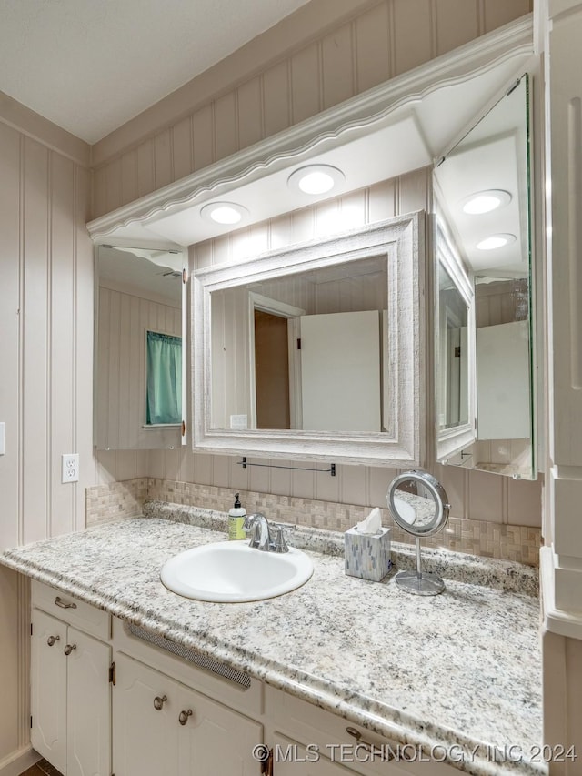 bathroom with decorative backsplash, a decorative wall, and vanity