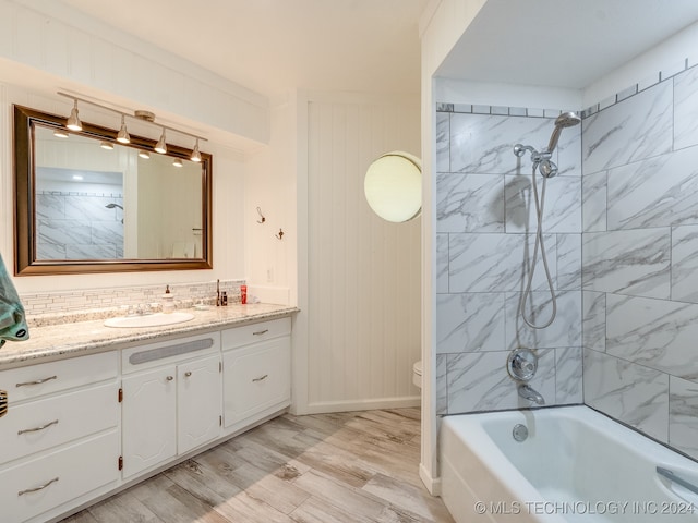 full bathroom featuring toilet, crown molding, tiled shower / bath, hardwood / wood-style flooring, and vanity