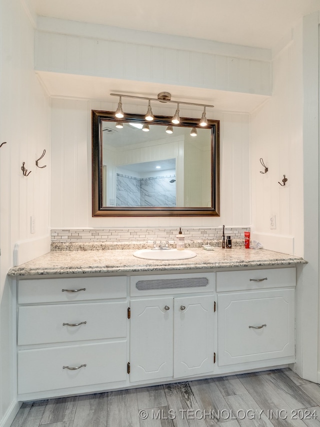 bathroom featuring wood-type flooring, vanity, and decorative backsplash