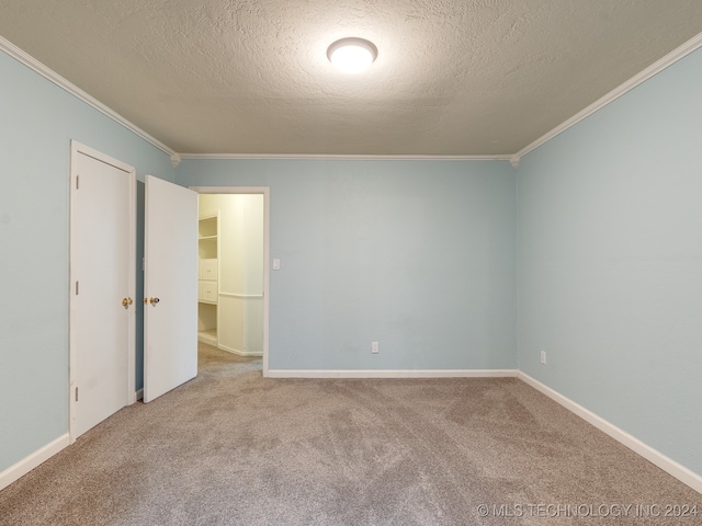 spare room with crown molding, a textured ceiling, and light carpet