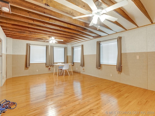 empty room with light wood-type flooring, ceiling fan, and beam ceiling