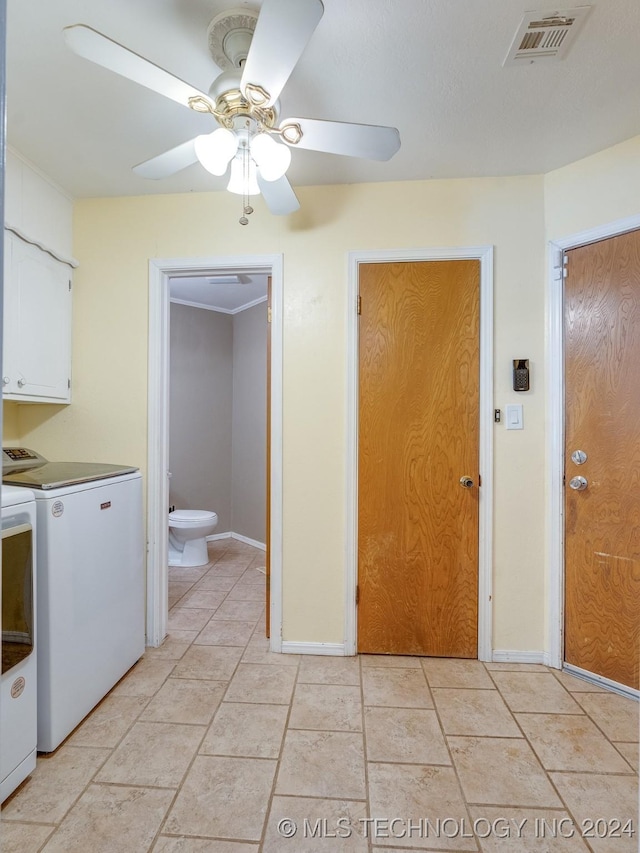 clothes washing area featuring ceiling fan, visible vents, washing machine and dryer, baseboards, and cabinet space