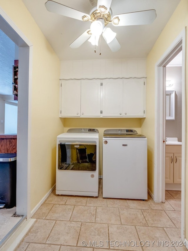 clothes washing area with a ceiling fan, stone finish flooring, baseboards, cabinet space, and washer and clothes dryer