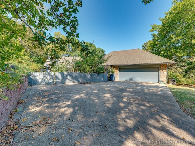view of side of property with roof with shingles, aphalt driveway, a garage, and fence