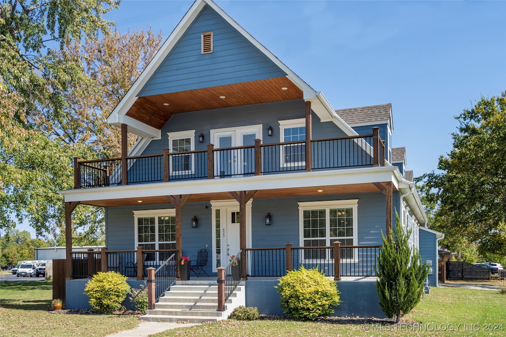 view of front facade with a porch, a front yard, and a balcony