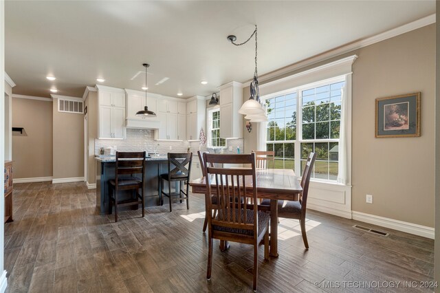 dining area featuring dark wood-type flooring and ornamental molding