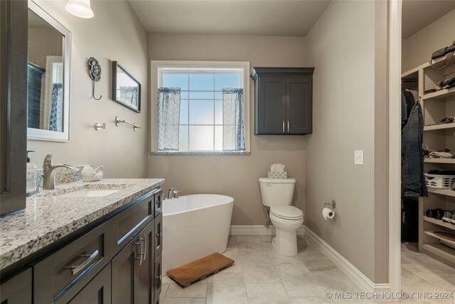 bathroom featuring vanity, a tub to relax in, tile patterned flooring, and toilet