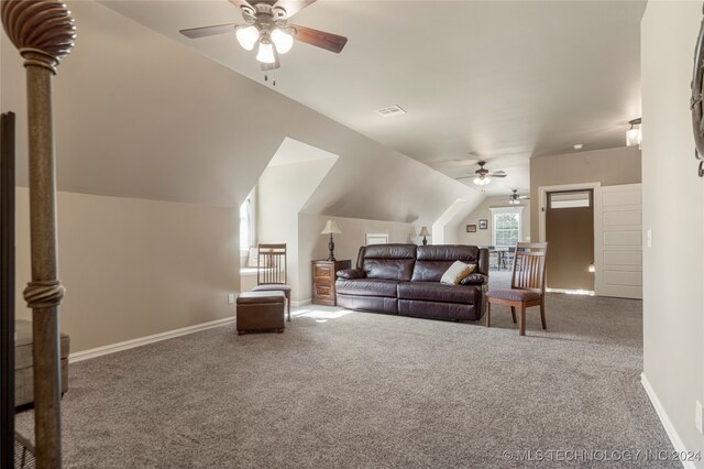 living room with lofted ceiling, ceiling fan, and carpet