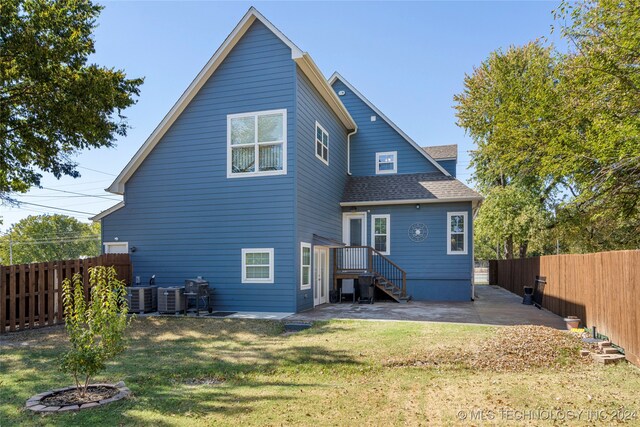 rear view of property with cooling unit, a yard, and a patio