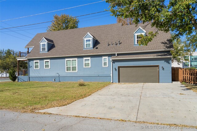 cape cod home featuring a garage and a front lawn