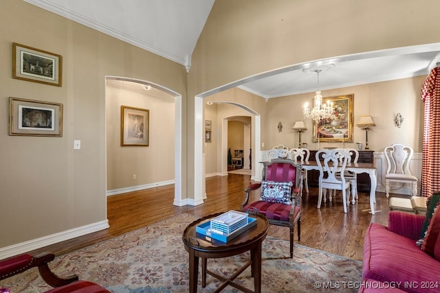 living room featuring wood-type flooring, ornamental molding, vaulted ceiling, and a notable chandelier