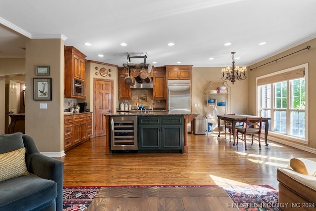 kitchen with an island with sink, hardwood / wood-style flooring, wine cooler, and appliances with stainless steel finishes