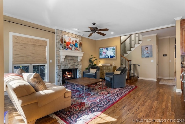 living room featuring wood-type flooring, a stone fireplace, crown molding, and ceiling fan