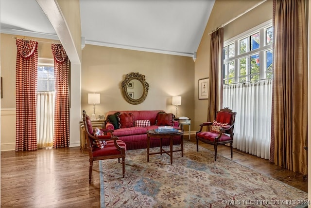 living room featuring lofted ceiling, crown molding, and wood-type flooring