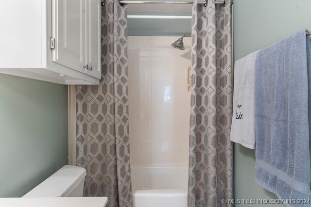 bathroom featuring shower / tub combo with curtain and toilet