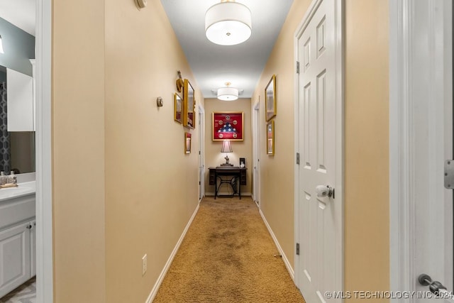 hallway with sink and light colored carpet