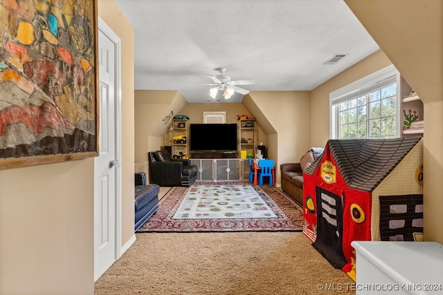 carpeted living room with ceiling fan and a textured ceiling