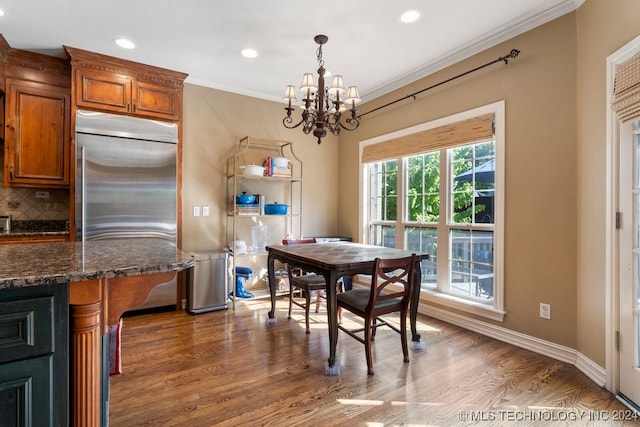 dining space with ornamental molding, an inviting chandelier, and dark hardwood / wood-style floors