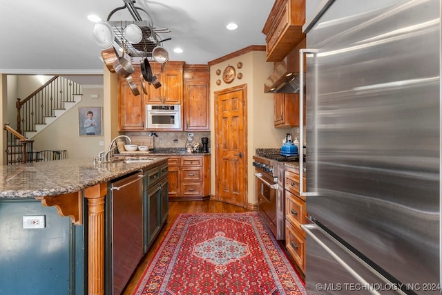 kitchen with appliances with stainless steel finishes, dark wood-type flooring, sink, and ornamental molding