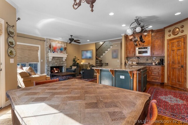 kitchen featuring a kitchen island with sink, a breakfast bar, tasteful backsplash, a fireplace, and ornamental molding