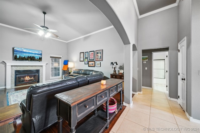 tiled living room featuring ornamental molding, ceiling fan, and a towering ceiling