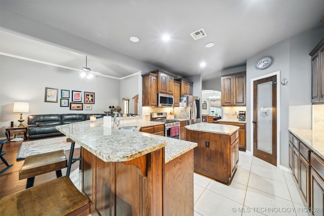 kitchen with kitchen peninsula, a kitchen island, stainless steel appliances, and tasteful backsplash